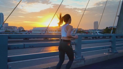 日落时年轻女子慢跑过桥的慢动作