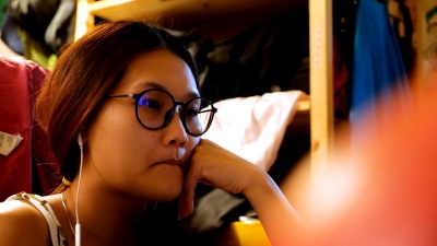 年轻的亚洲女性用耳机看电影。
