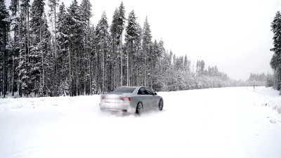 一辆汽车在森林公路上的大雪中经过