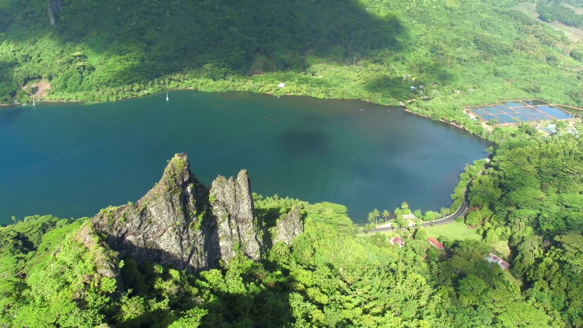  空中特写 在热带岛屿上高耸的岩石山脊上空飞行，有异国情调的海滩，广阔的深海海湾和郁郁葱葱的棕榈树和金合欢树丛林