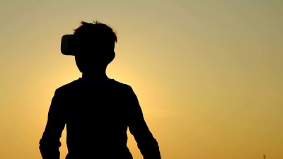 一个小男孩在自然界外面使用虚拟现实眼镜