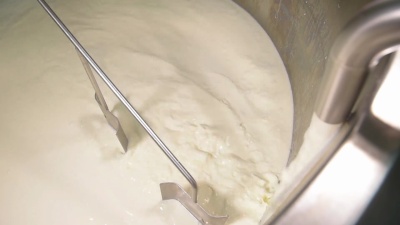 干酪制造者将牛奶煮沸到混合锅中制作奶酪
