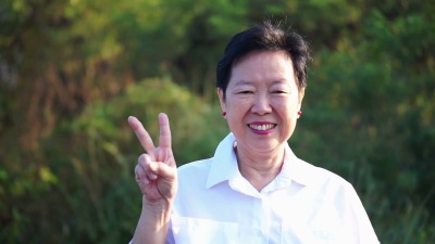 亚洲资深女性竖起大拇指微笑，以绿色自然为背景