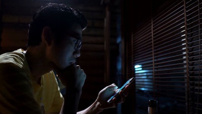 亚洲男子晚上在咖啡馆/酒吧使用移动智能手机