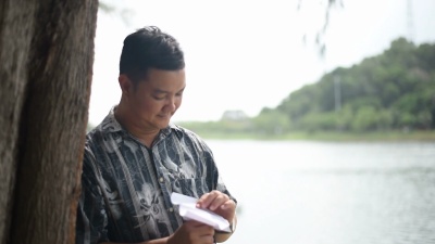 这个男人把纸飞机扔在湖边。