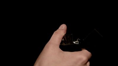 女人的手在黑色背景下点燃复古打火机