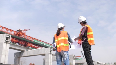 建筑师和工程师带着蓝图在施工现场交谈