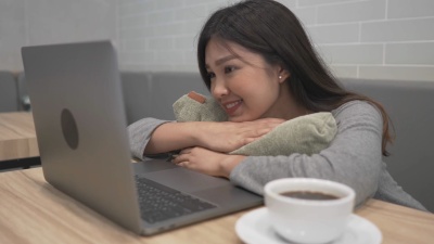 快乐的微笑的女人在放松的时候在咖啡馆里用笔记本电脑在线看视频
