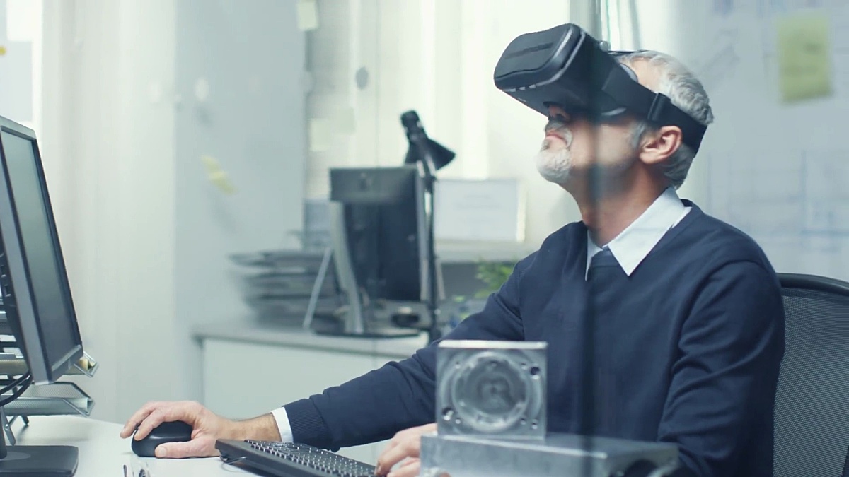 虚拟现实工程师使用VR眼镜工作，同时在他的个人电脑上编程。