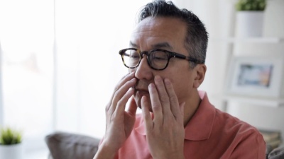 戴眼镜的疲惫男人在家里揉眼睛