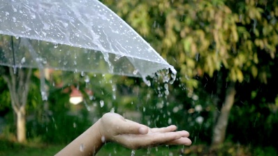 女士手的特写用雨伞触摸一滴雨