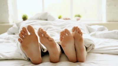 特写镜头年轻、美丽、充满爱意的夫妇在毯子下玩耍跳舞，早上醒来时躺在床上