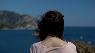 后视图-在阳光灿烂的夏日，一个身份不明的戴帽子的年轻女孩张开双臂欣赏自由和自然，慢动作