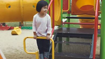 Asian baby girl is enjoying to climb and play equipment at the playground