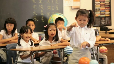 Asian Child in Classroom Presenting Model Solar System to Camera / Richmond, Virginia, USA