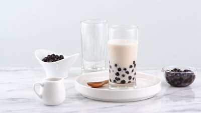 Tasty tapioca pearl bubble milk tea in glass, popular drink in taiwan on bright marble table and white tray, homemade concept. 4K Zoom in shot video
