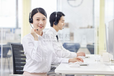 人物系列写实坐在办公室的电脑前带着耳机为客户解答的客服
