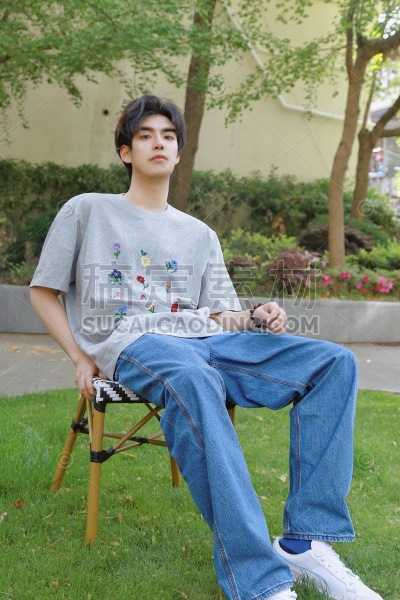 年轻男性坐在草地上的椅子上