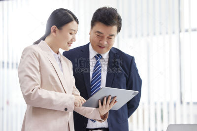 人物系列写实站在一起看平板资料的同事