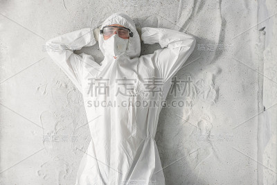 一名男子身穿白色防护服，戴着呼吸器和塑料透明眼镜。