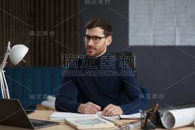 建筑师在办公室里设计蓝图。工程师检查建筑平面图，为建筑工程画草图。长着胡须的英俊男子坐在工作场所的肖