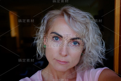 一个漂亮的女人的近距离肖像在金色卷发站在门口