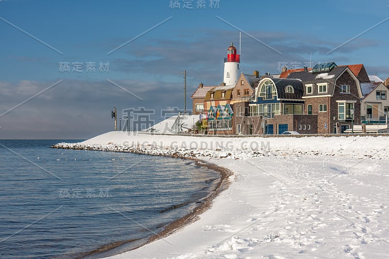 荷兰海滩上覆盖着雪和灯塔Urk的景色