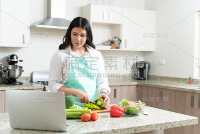 年轻漂亮的女人在厨房准备蔬菜沙拉