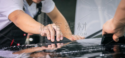 汽车包装专家将乙烯基箔或薄膜放在汽车上以保护汽车。选择性聚焦-薄膜影响