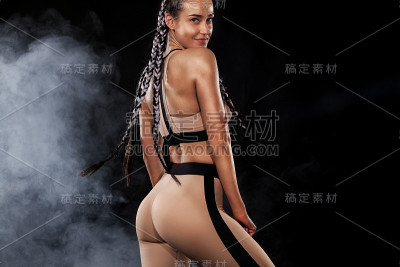 一个强壮的运动女性在黑色背景穿着黄色运动服，健身和运动动机。运动概念与复制空间。