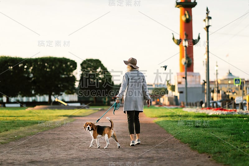 快乐的女人在公园的小巷里遛狗