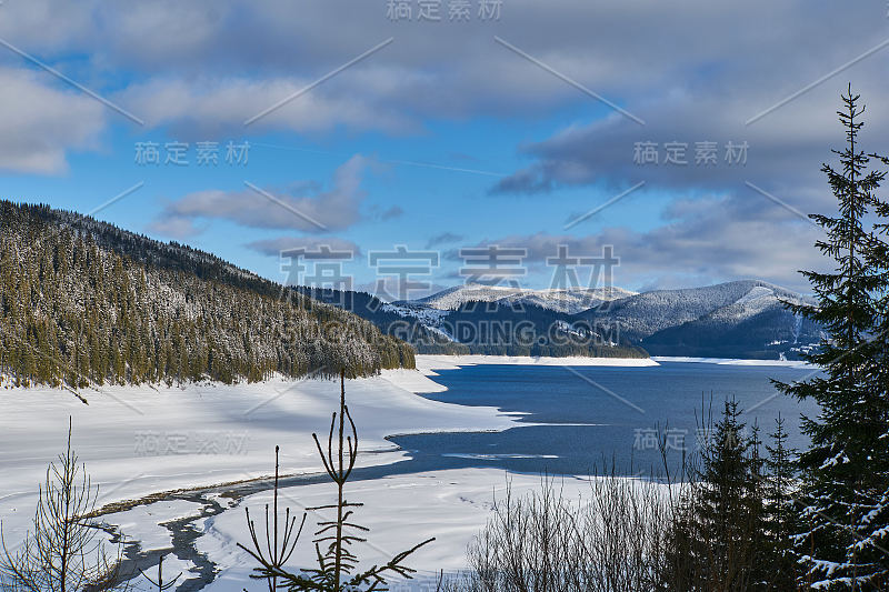 冬季景观从山上有湖，冷杉林，雪和蓝天与云