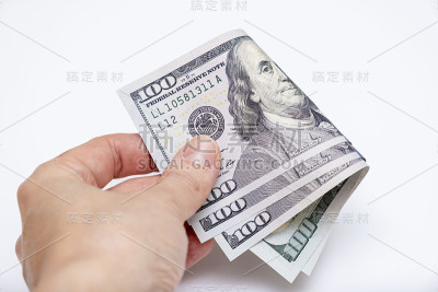 手里拿着折叠的美钞，有省钱的理念