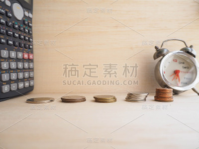 木材背景上的硬币塔和计算器