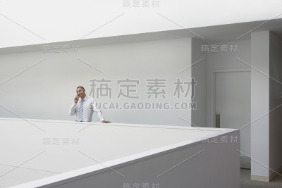 在走廊栏杆边使用手机的商人