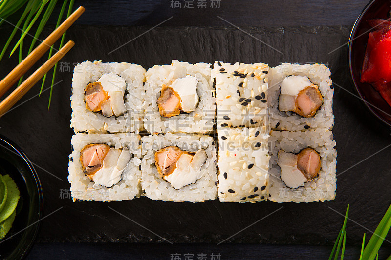 一套寿司卷与芥末和生姜在黑色的背景。日本东方美食