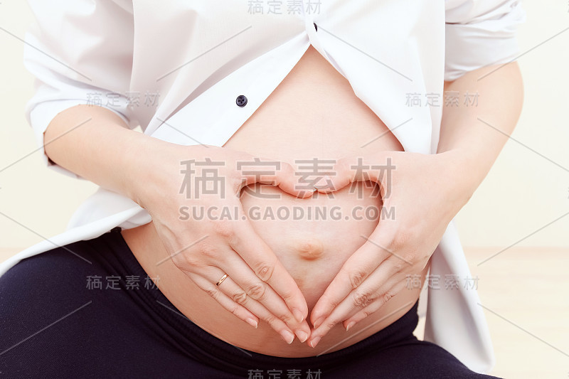 孕妇把手放在她心形的肚子上。28、母性与怀孕观念，家庭幸福