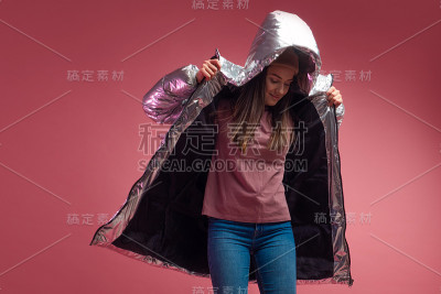 时尚和现代的年轻女子在一个蓬松的轻羽绒服扔在她的头上兜帽。
