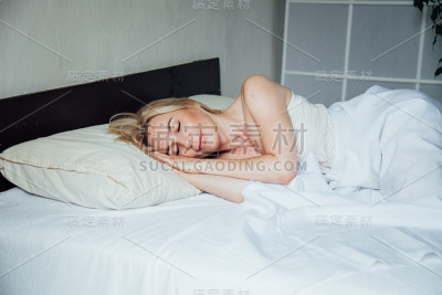 金发女郎在卧室的床上睡了一觉后醒来