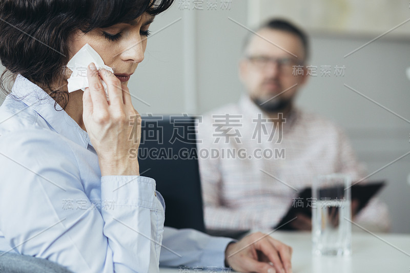 美丽的女人一边和治疗师说话一边擦眼泪