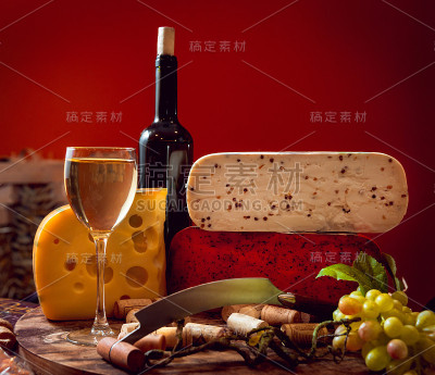 黑桌子上放着奶酪和葡萄酒。