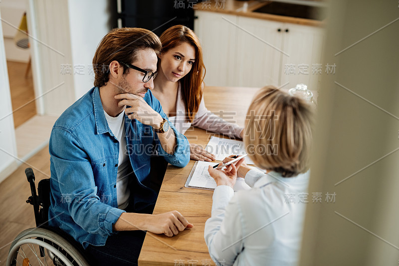 年轻夫妇和房地产经纪人在家里用触控板开会。