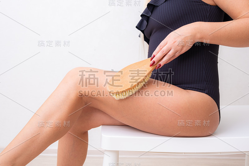 女性腿部用瘦身按摩刷。身体护理和美容理念