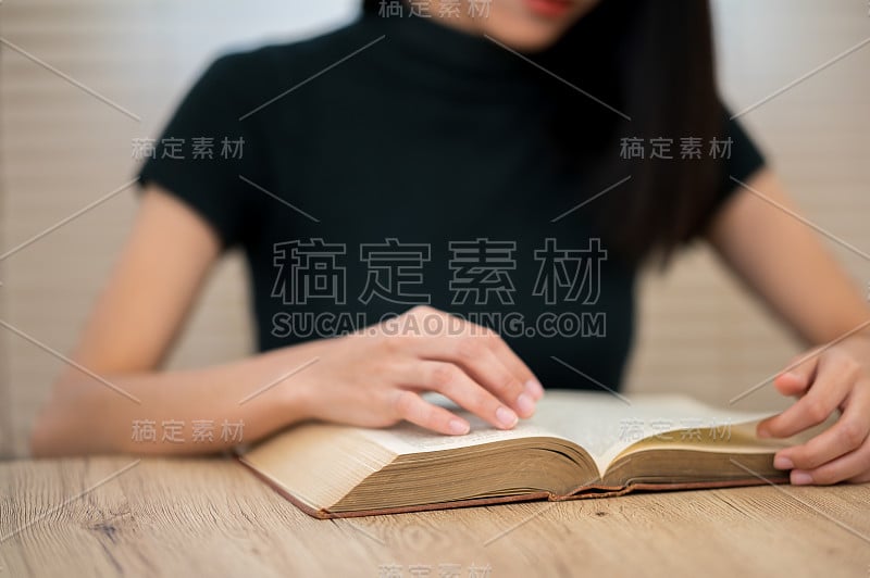 一位穿着黑色衬衫的亚洲女学生正坐在大学里读书