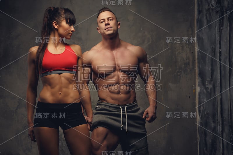 赤膊健美运动员和健身妇女在运动服。
