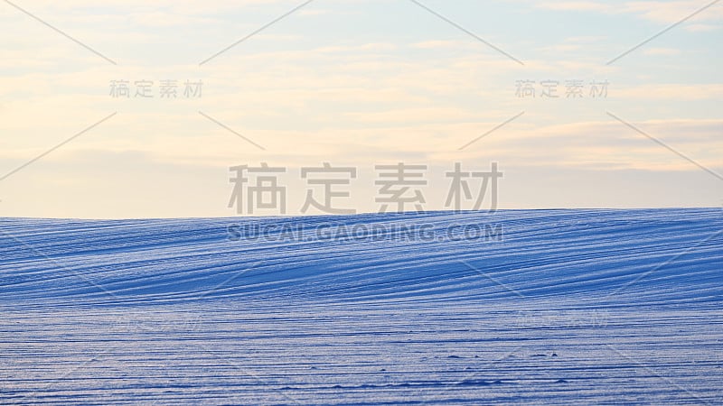 冬天的风景。日落时分白雪覆盖的农田。