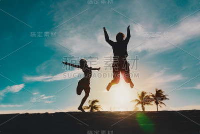 快乐的父亲和儿子在日落海滩上跳跃