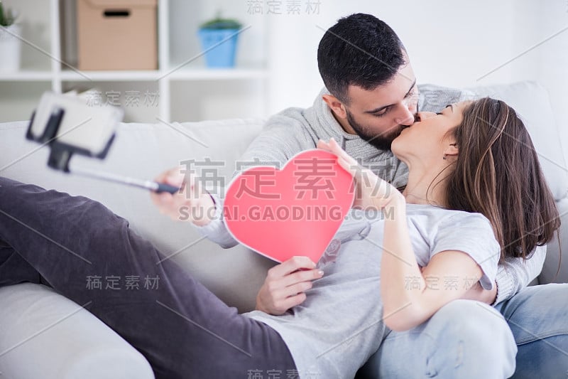 幸福的年轻美丽的夫妇用智能手机拍照