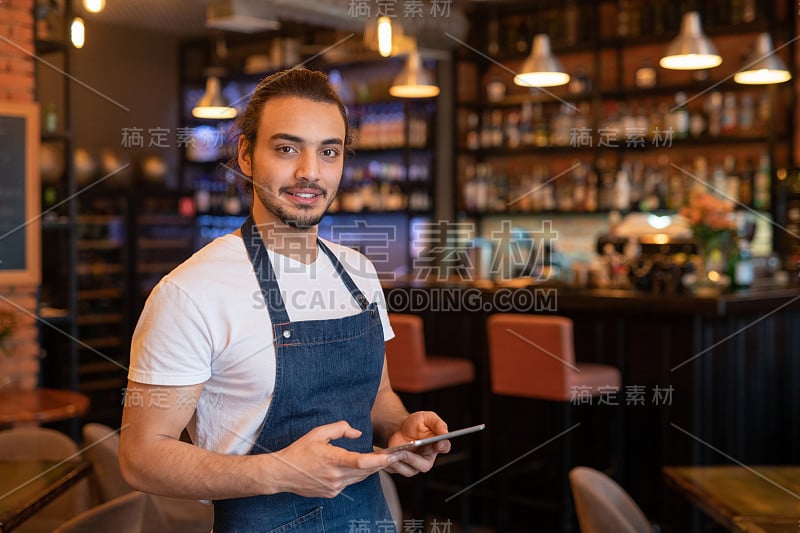 当代年轻帅气的服务生用平板电脑为客户在线点菜