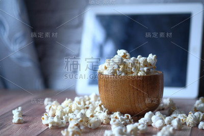 爆米花在碗和数字平板电脑在桌子上的特写